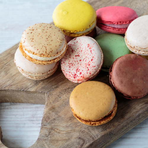 Macarons sit on a wooden board.