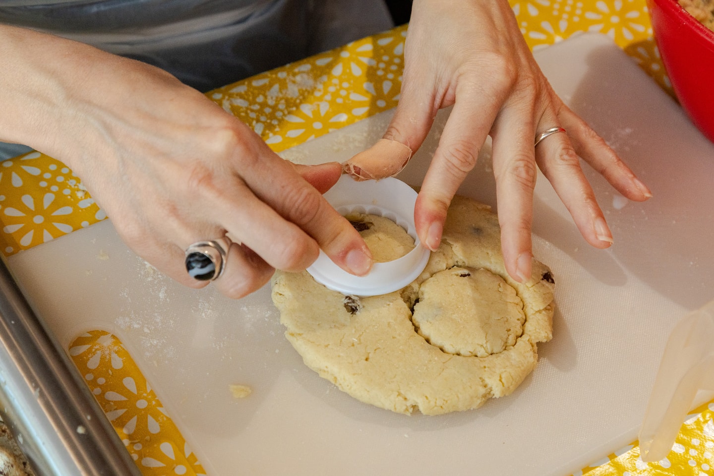 A woman presses a cookie cutter into fresh dough to cut out her scones