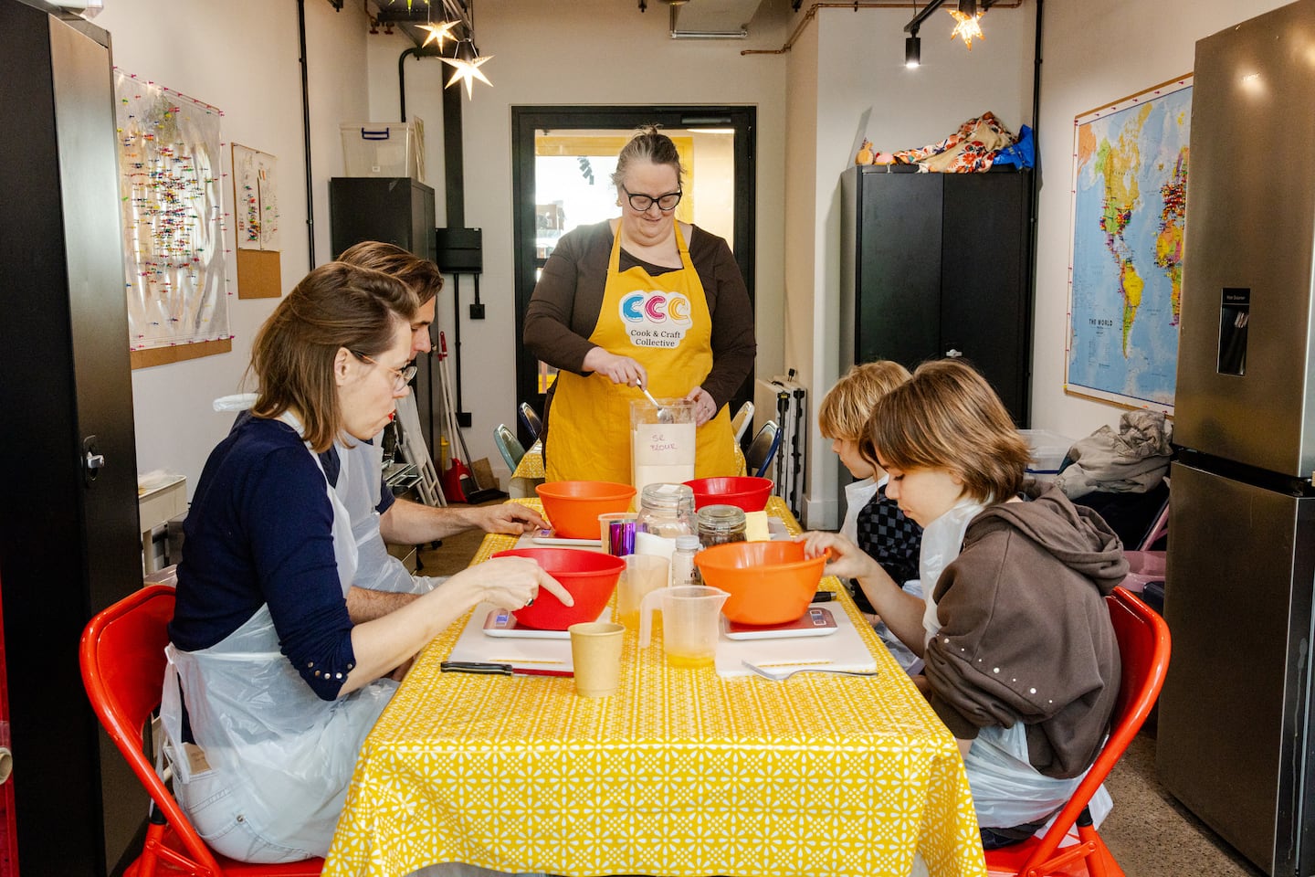 Two adults and two children sit around a table preparing their scones