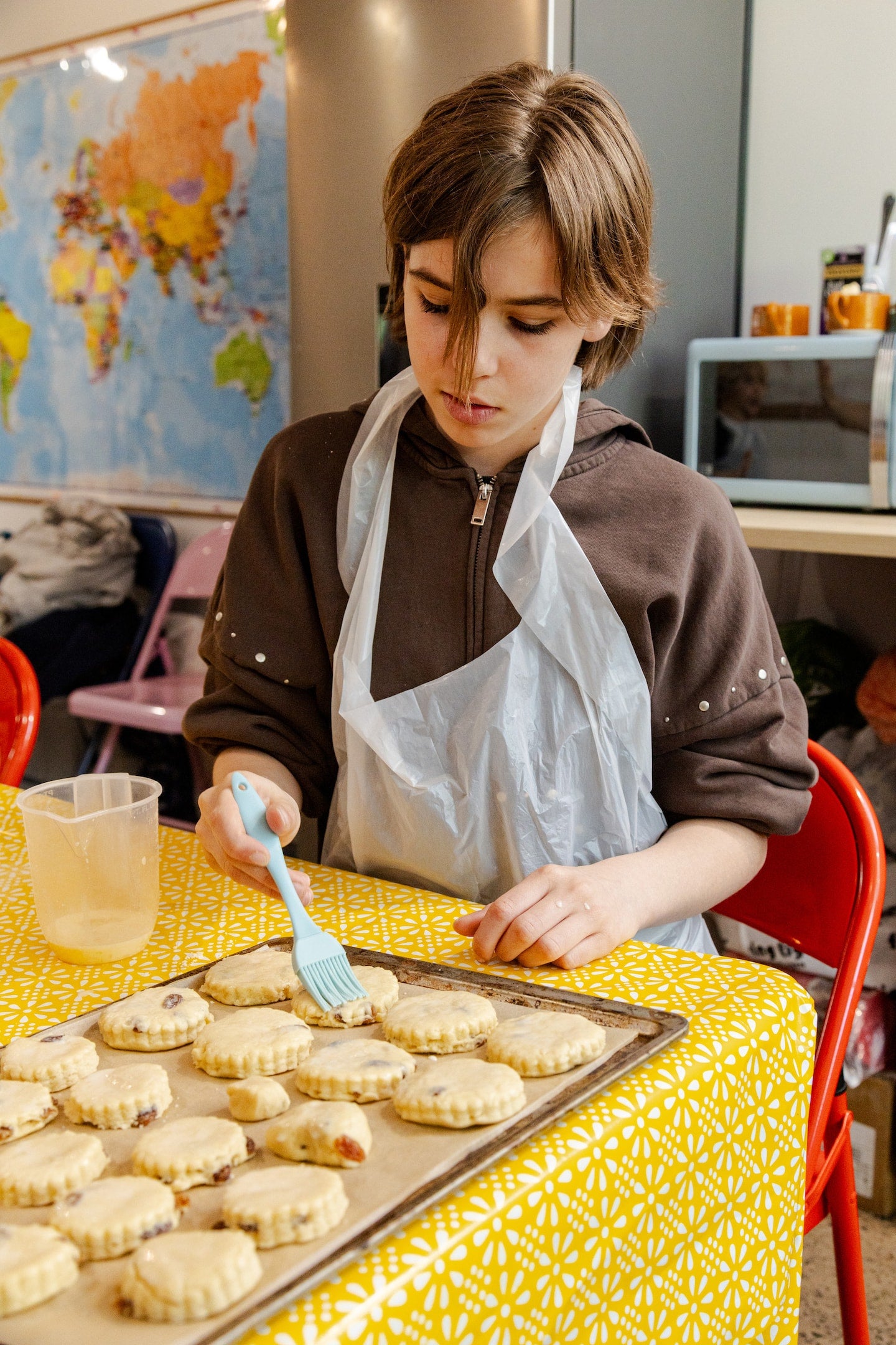 A child brushes their scones with melted butter to get them ready for the oven