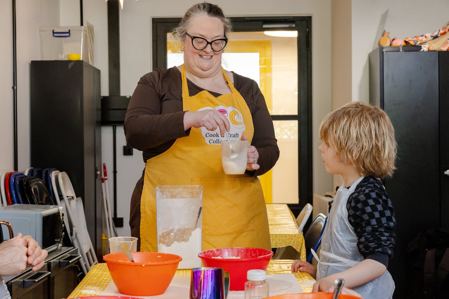 Course leader Joanna shows a small child how to make dough.