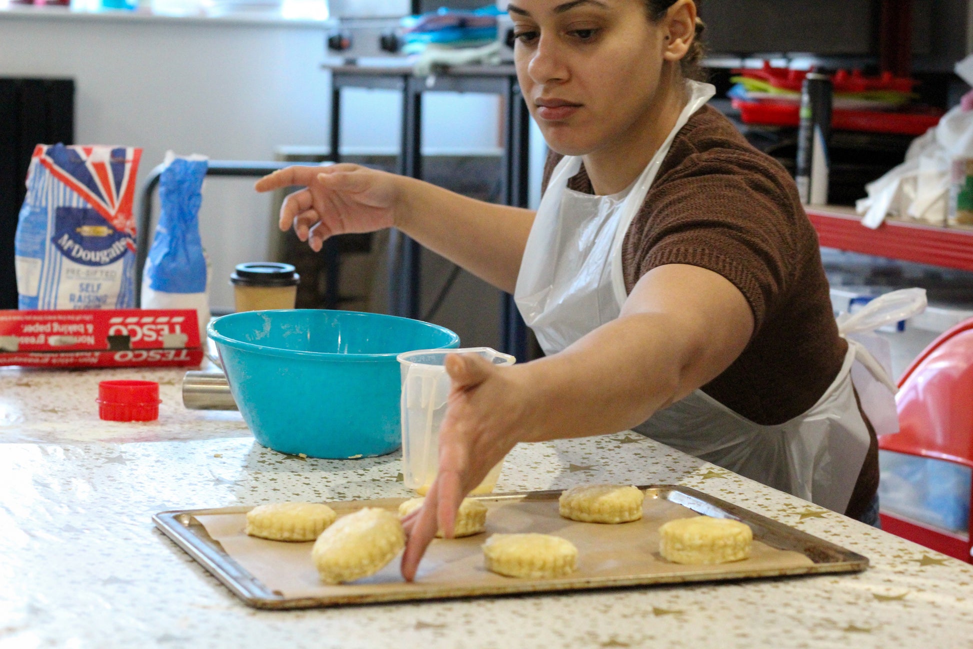 A woman lays out her freshly-made scones on a baking sheet ready for the oven