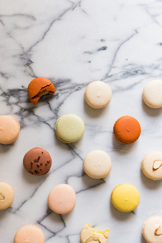 A variety of colorful macarons arranged on a marble surface.