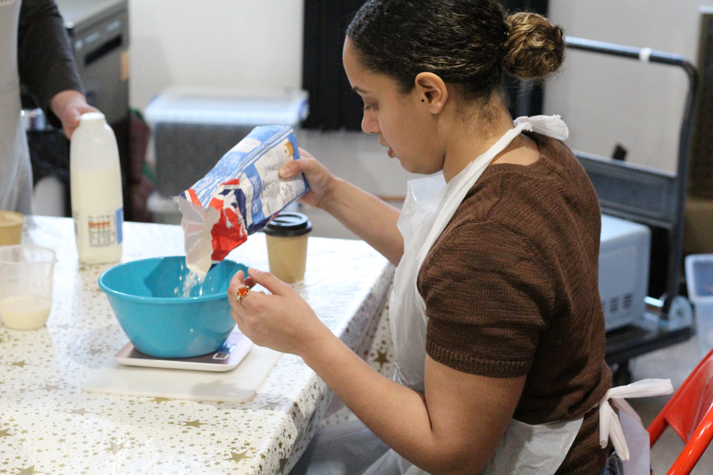A woman pours flour into a blue bowl