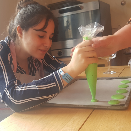 A woman pipes her macaron bases onto a baking sheet