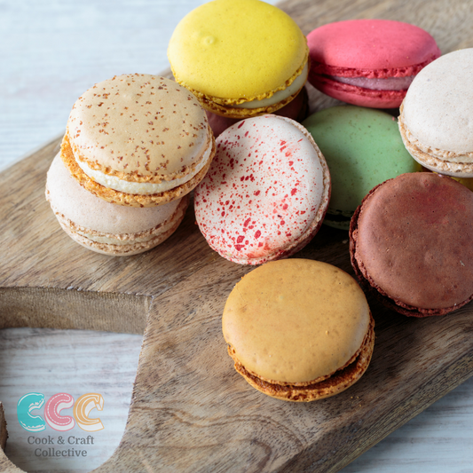 French Macarons are easier than you think when you buy one of our kits. Image shows a collection of different flavoured and coloured macarons on a wooden chopping board. 