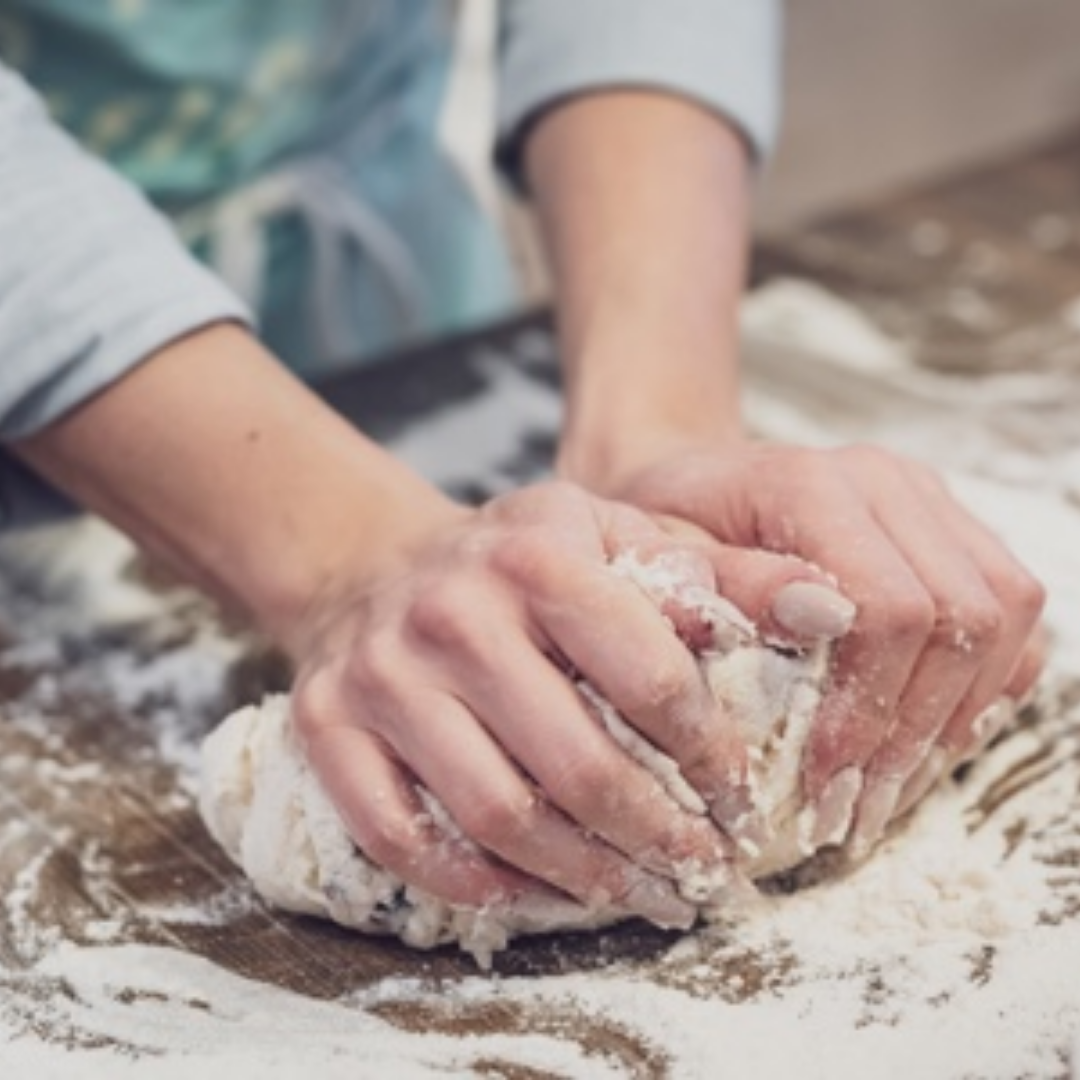 Learn all you need to know on this virtual bread making workshop. Image shows a person kneading bread dough covered in flour.